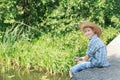 Angling boy with wooden rustic fishing rod sitting on concrete bridge Royalty Free Stock Photo