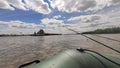 angling or fishing from boat, fishing rod with bait on background of river, or lake and blue sky. Photo from boat