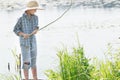 Angling teenage boy looking at handmade green twig fishing rod in his arms Royalty Free Stock Photo