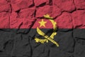 Angola flag depicted in paint colors on old stone wall closeup. Textured banner on rock wall background