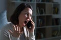 Angry adult woman screaming calling on phone at night at home Royalty Free Stock Photo