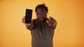 Angry african american black man showing phone screen and pointing finger towards camera. Cheated husband accusing his Royalty Free Stock Photo