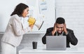 Angry African American lady boss with loudspeaker screaming at frightened male employee in office Royalty Free Stock Photo