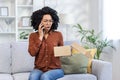 Angry African American young woman talking on the phone. He sits on the sofa at home and anxiously looks at the open box Royalty Free Stock Photo