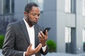 Angry and angry boss talking and shouting on mobile phone, african american businessman in business suit walking outside Royalty Free Stock Photo