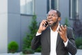 Angry and angry boss talking and shouting on mobile phone, african american businessman in business suit walking outside Royalty Free Stock Photo