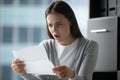 Angry annoyed young businesswoman reading letter, received bad news