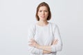 Closeup of angry annoyed young woman in longsleeve standing with arms crossed and feels irritated isolated over white backgound Royalty Free Stock Photo