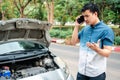 Angry Asian man and using mobile phone calling for assistance after a car breakdown on street. Concept of vehicle engine problem Royalty Free Stock Photo