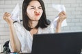 Angry Asian woman sitting at desk hand crumpling paper on table