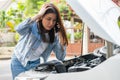 Angry Asian woman and using mobile phone calling for assistance after a car breakdown on street. Concept of vehicle engine problem Royalty Free Stock Photo