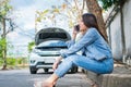 Angry Asian woman and using mobile phone calling for assistance after a car breakdown on street. Concept of vehicle engine problem Royalty Free Stock Photo