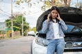 Angry Asian woman and using mobile phone calling for assistance after a car breakdown on street. Concept of vehicle engine problem Royalty Free Stock Photo