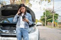 Angry Asian woman and using mobile phone calling for assistance after a car breakdown on street. Concept of vehicle engine problem Royalty Free Stock Photo