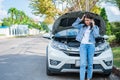 Angry Asian woman and using mobile phone calling for assistance after a car breakdown on street. Concept of vehicle engine problem Royalty Free Stock Photo