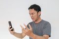 Angry Asian young man get mad on the smartphone. Indonesia Man wear black shirt grey background