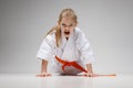 Angry baby girl in a kimono is doing push-ups on a white background, karate training Royalty Free Stock Photo