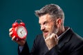 Angry bearded businessman holding alarm clock, shouting and showing fist at it. Time management concept Royalty Free Stock Photo