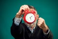 Angry bearded businessman holding alarm clock, shouting and showing fist at it. Time management concept Royalty Free Stock Photo