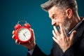Angry bearded businessman holding alarm clock and shouting at it. Time management concept Royalty Free Stock Photo