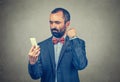 Man looking at his phone and clenching his fist to the cellphone Royalty Free Stock Photo