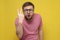 Angry bearded man in glasses, shows with his fingers number two, sign 2 and screams in annoyed, on a yellow background Royalty Free Stock Photo