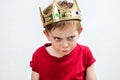 Angry beautiful spoiled kid wearing king crown facing unhappy parenthood