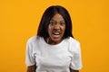 Angry black lady yelling at camera, yellow background