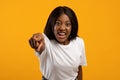 Angry black lady yelling and pointing at camera, yellow background