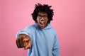 Angry black teenager shouting and pointing at camera on pink studio background. Negative emotions concept