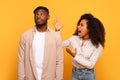 Angry black woman yelling at indifferent man on yellow background