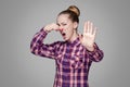 Angry blonde girl in red, pink checkered shirt, collected bun ha Royalty Free Stock Photo