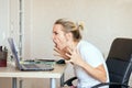 Angry blonde woman working on laptop at home and screaming She`s upset. Freelance, work at home concept Royalty Free Stock Photo