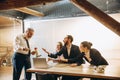 Angry boss with megaphone screaming at employees in office, scared and annoyed colleagues listening at the table