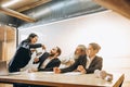 Angry boss with megaphone screaming at employees in office, scared and annoyed colleagues listening at the table