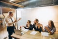 Angry boss with megaphone screaming at employees in office, scared and annoyed colleagues listening at the table