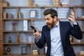 Angry boss quarreling and shouting on phone call, man in business suit at work inside office, nervously talking with Royalty Free Stock Photo