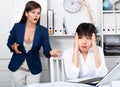 Angry boss screaming to young female manager during working