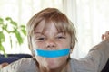 Angry boy with his mouth taped shut - silenced child concept