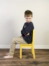 Angry boy on a yellow time out chair Royalty Free Stock Photo