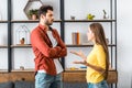 Angry boyfriend standing with crossed arms while girlfriend quarreling in