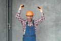 Angry builder man wearing construction uniform and safety helmet over gray wall background shouting and screaming with Royalty Free Stock Photo