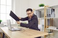 Angry business man on workplace in office trying to destroy the monitor with his keyboard. Royalty Free Stock Photo