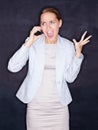 Angry business woman screaming over mobile phone against black. Angry young business woman screaming over the cellphone Royalty Free Stock Photo