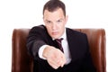 Angry businessman seated on a chair, pointing Royalty Free Stock Photo