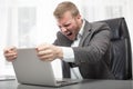 Angry businessman shaking his laptop computer Royalty Free Stock Photo