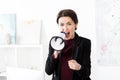 Angry businesswoman screaming in megaphone in office, looking Royalty Free Stock Photo