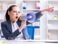 Angry businesswoman yelling with loudspeaker in office