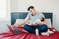 Angry busy Caucasian father with newborn Asian Chinese baby working from home.