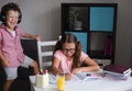 Angry caucasian girl with eyeglasses make homework. Brother disturb.